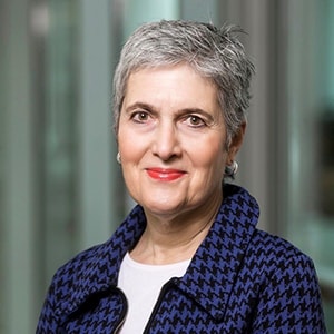 A woman with salt and pepper hair smiles at the camera.