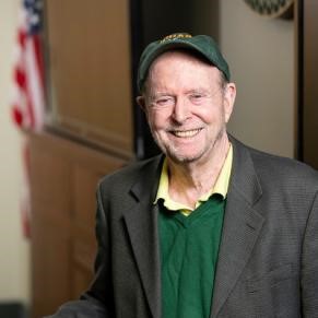A man in a ball cap in a sport coat smiles at the camera.