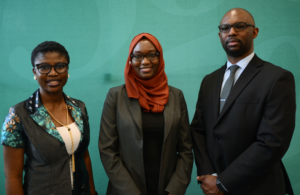 three adults before a green background