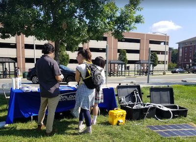 students looking at an exhibit on Merten Lawn