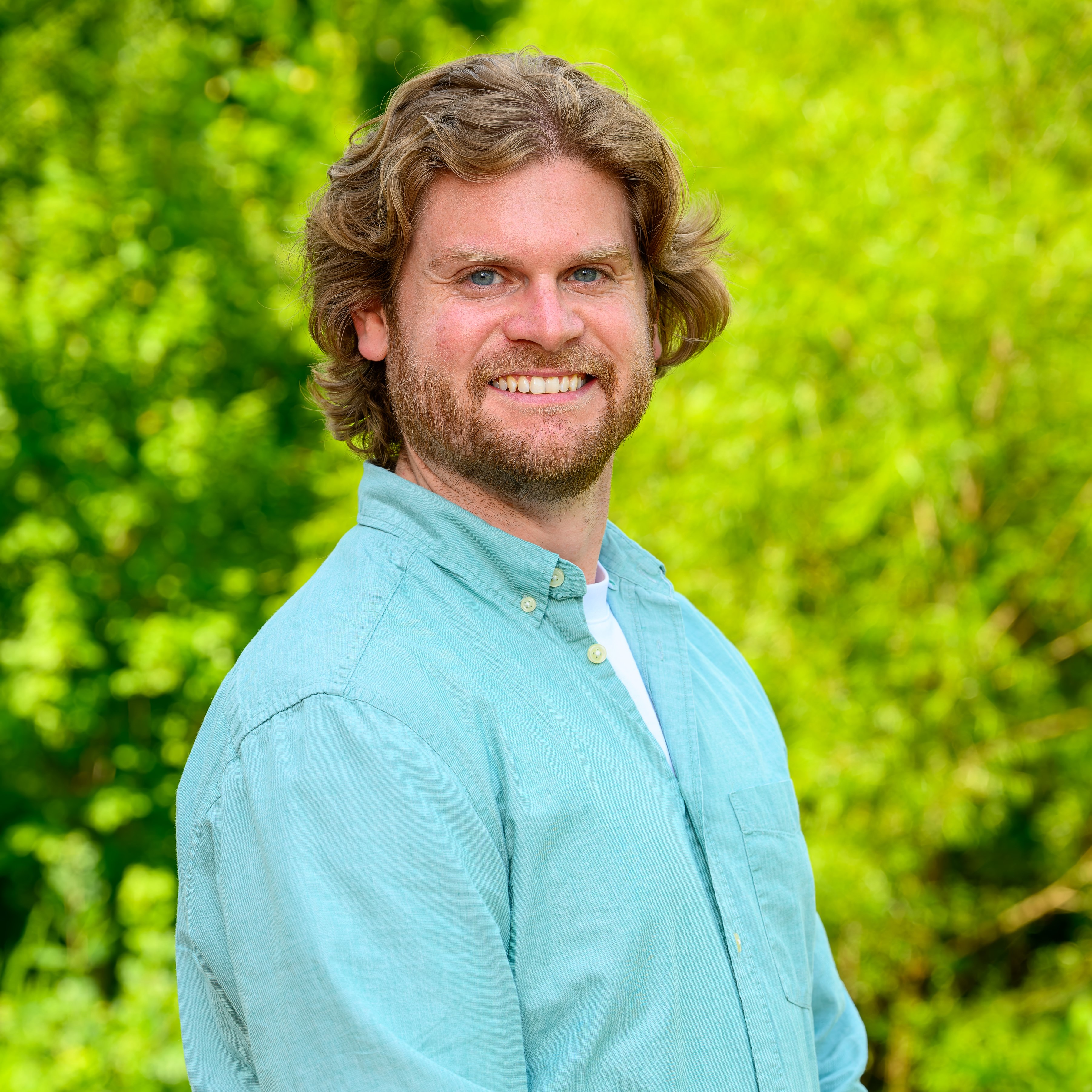 Colton Goodman in a blue button-up smiling 