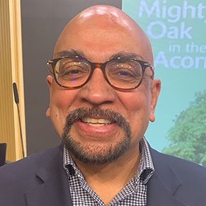 A bald man with a goatee and eyeglasses smiles at the camera.