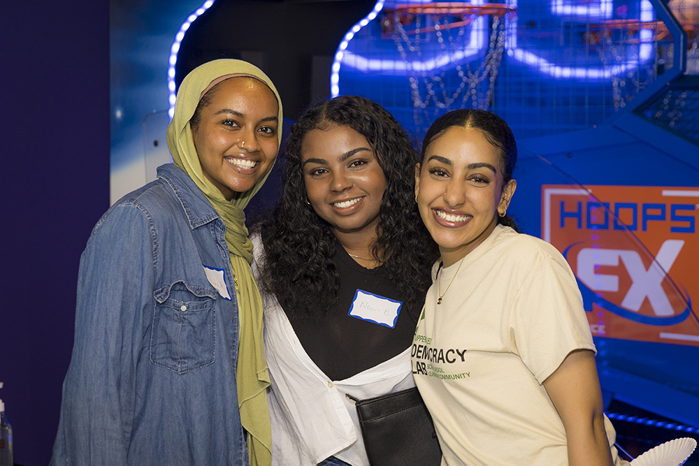 Three young women stand and smile at the camera.