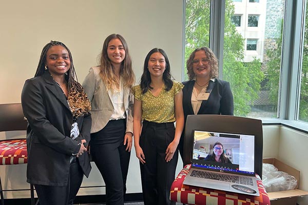 Three students standing with virtual image of teamate.