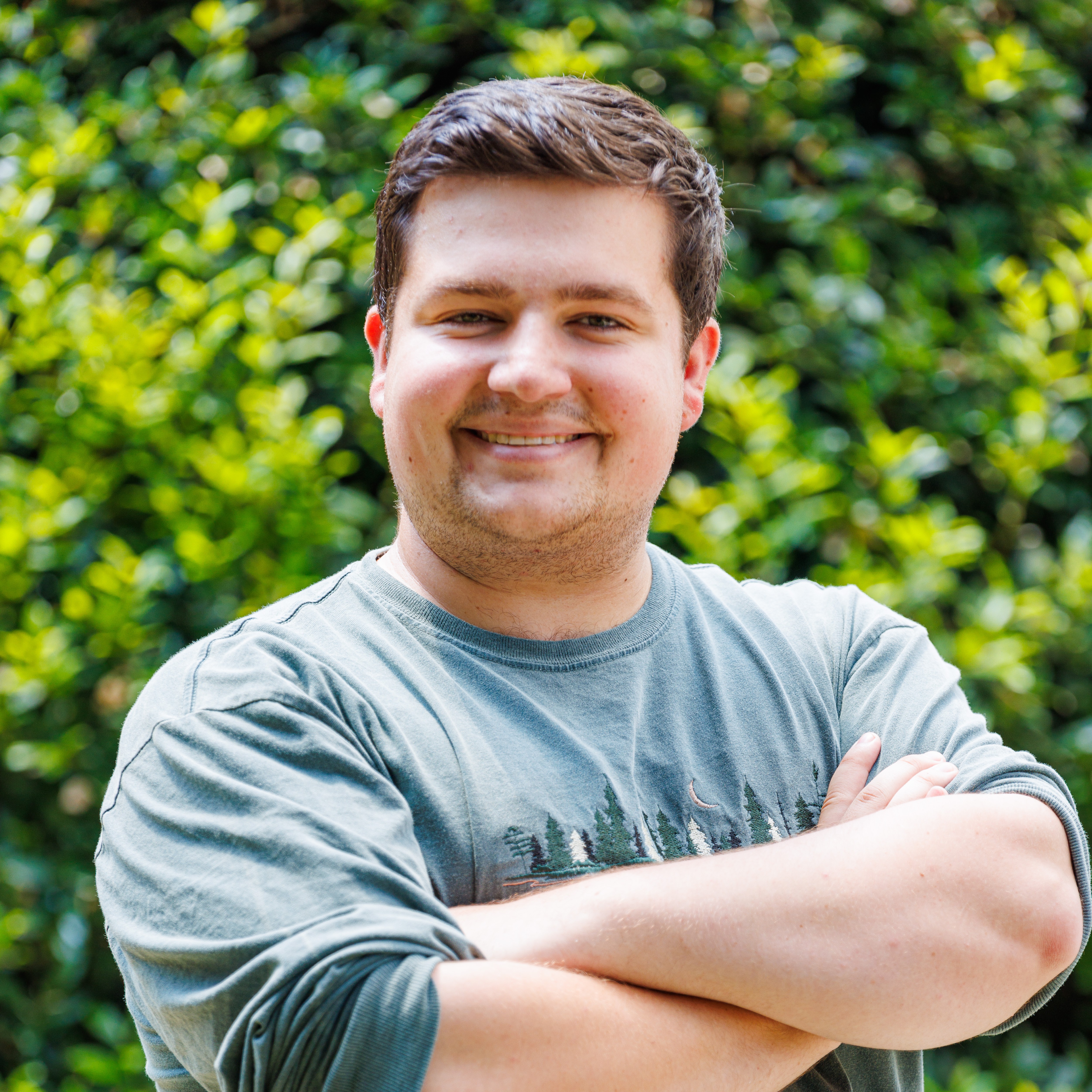 Ethan in a green longsleeve arms crossed smiling