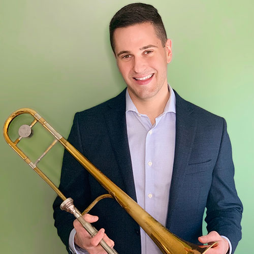 Aaron Eckert holding his trombone wearing a snazzy blue suit
