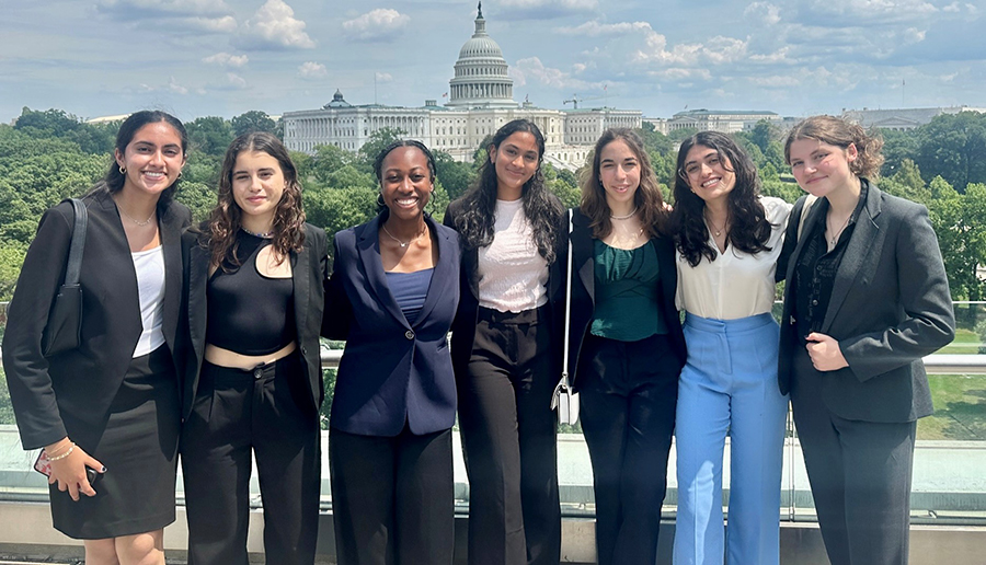 Seven women stand in front of the U.S. Capitol Building.