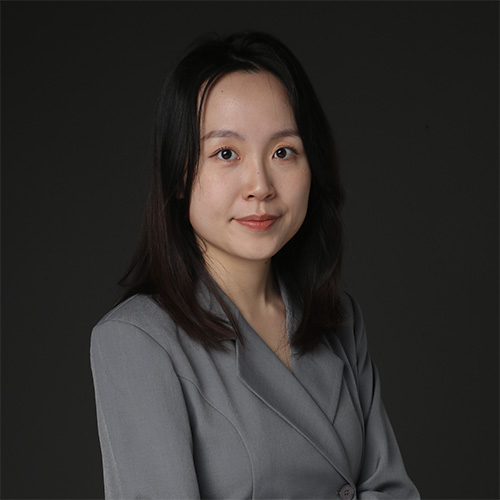 Young Asian woman wearing a gray blazer against a dark background