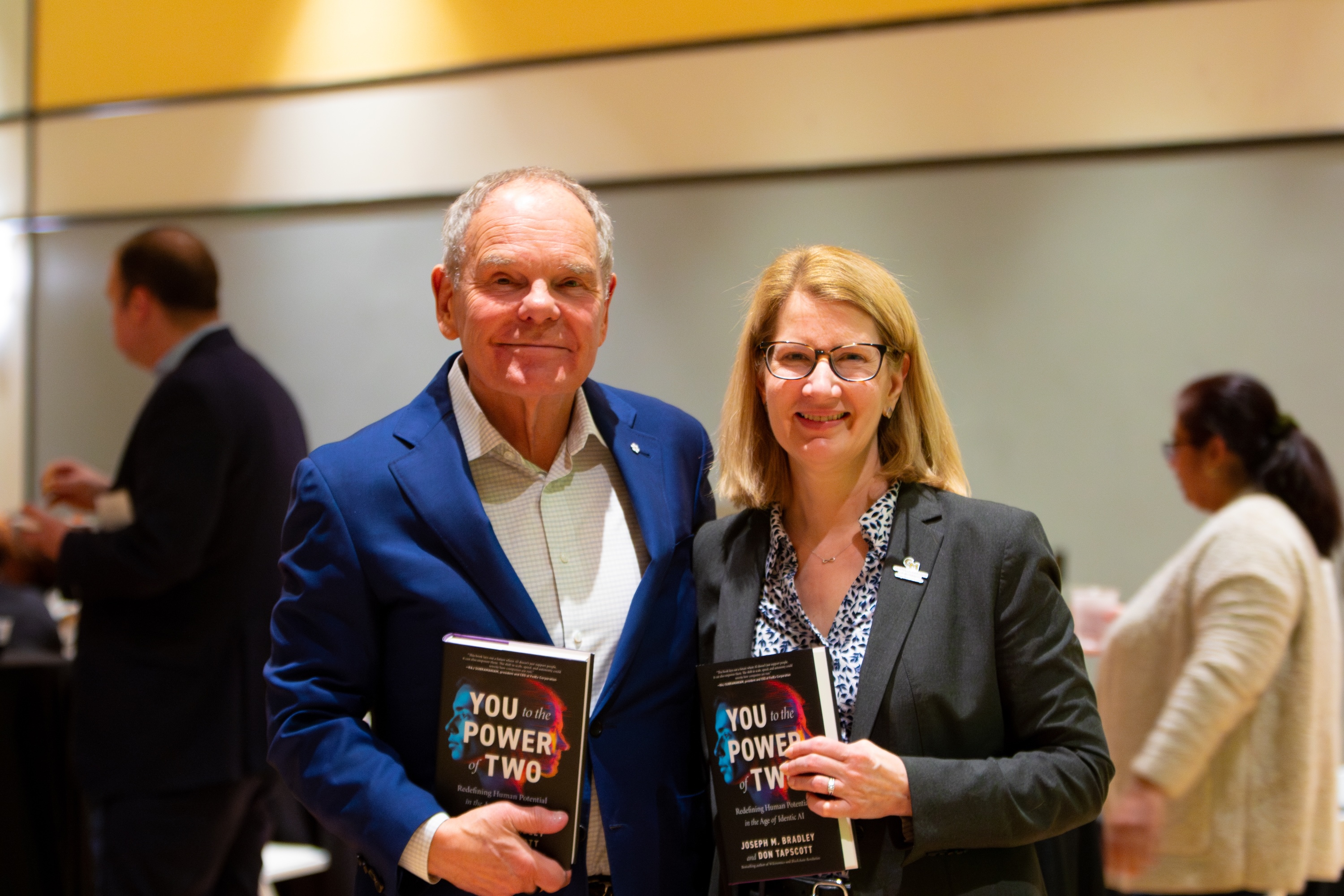 (Left to Right) Don Tapscott, Co-Founder and Executive Chairman of Blockchain Research Institute and Cheryl Druehl, Costello interim dean and professor of information systems and operations management each holding the new book, You to the Power of Two: Redefining Human Potential in the Age of Identic AI. Photo by Hannah Patterson/Costello College of Business.