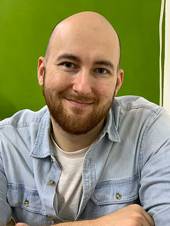 Alex Monea in a blue shirt in a green room. 