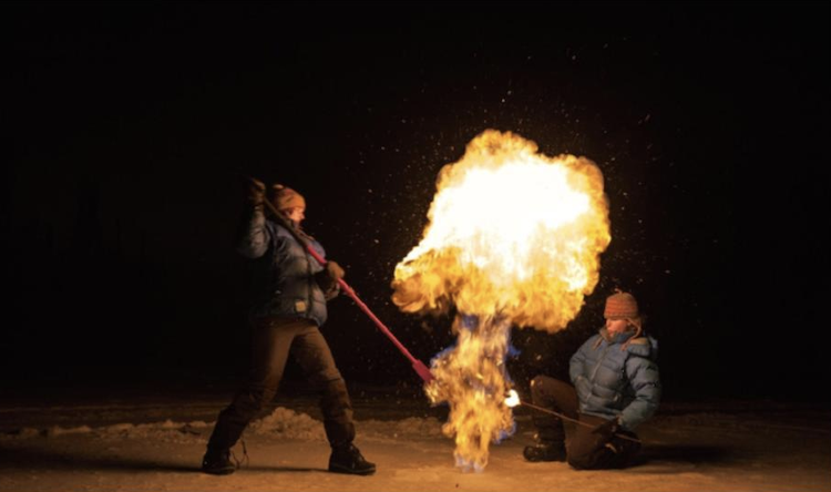 Picture of Dr. Miriam Jones and co-worker light fire to methane gas released from a permafrost lake.