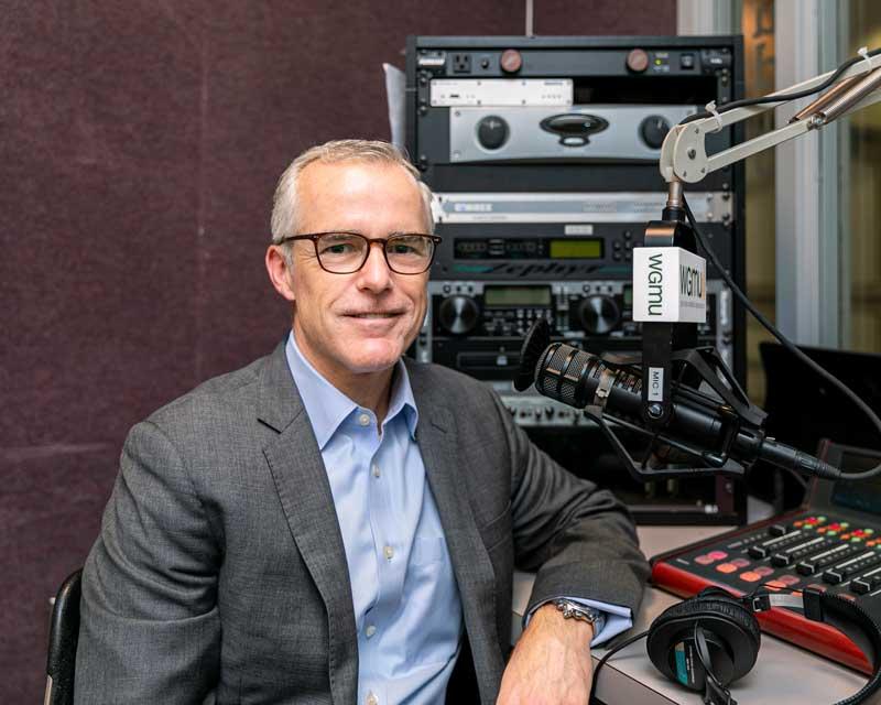 Andrew McCabe seated in front of the microphone in the recording booth at WGMU to speak with Gregory Washington in George Mason University's Access to Excellence podcast