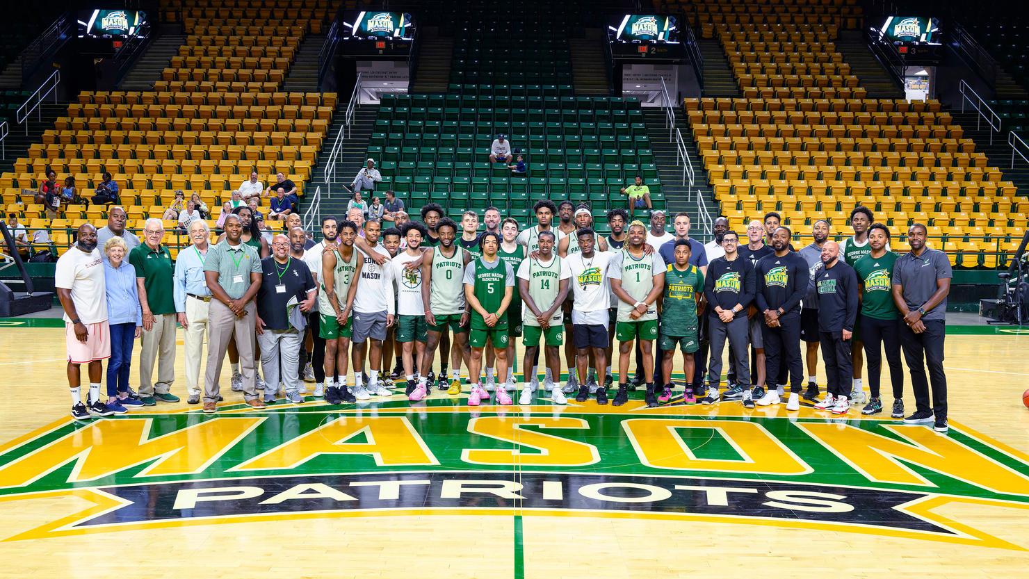 Basketball team and staff pose for a photo on a basketball court.
