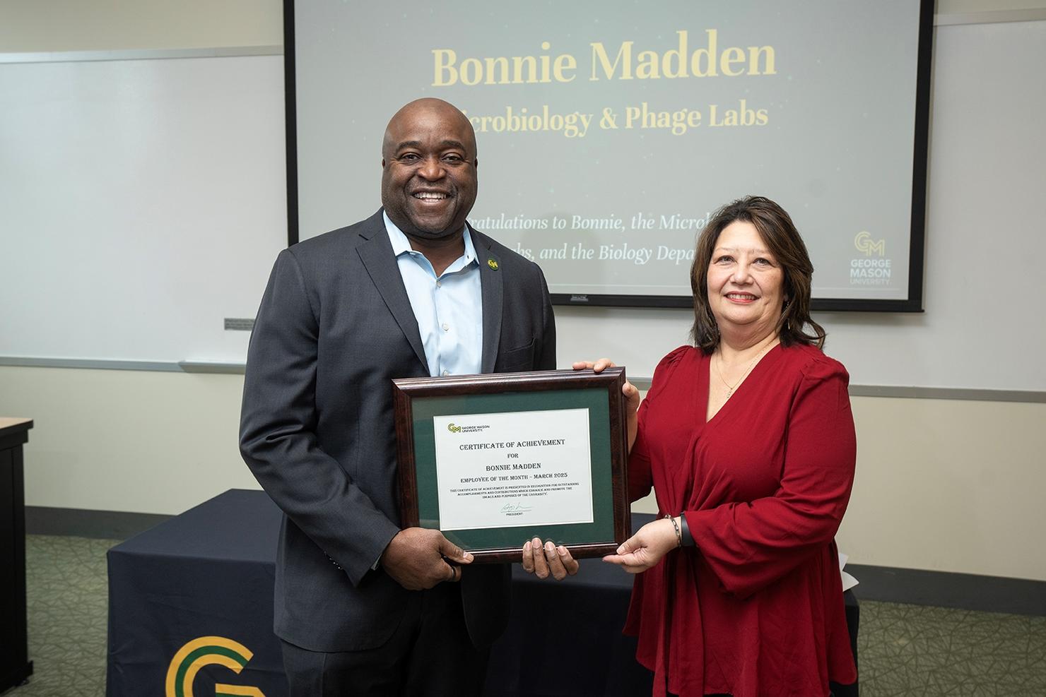 George Mason President Gregory Washington and Employee of the Month Bonnie Madden hold her certificate together at the ceremony