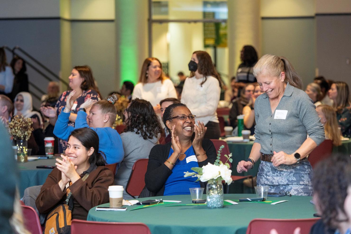 Faculty and staff laugh together at Green Day breakfast