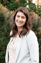 Gwendolyn Lewis Is standing outside in a light peach top and white blazer