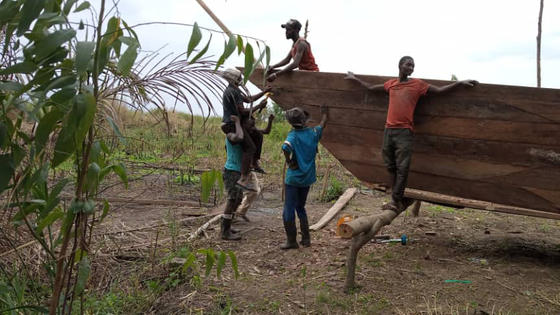 Six people, comprised of former armed group members and community members, working on a wooden ship in Mboko, South Kivu.