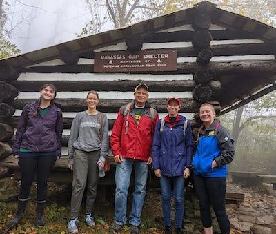A group of people named in the image caption stand before a structure. The sign on it reads Manassas Gap Structure.