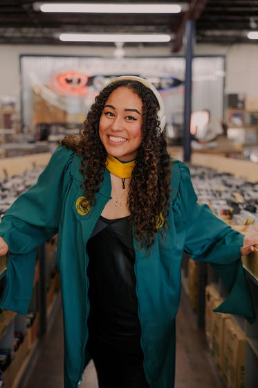 Blakely poses in her graduation gown and master's hood in a record store