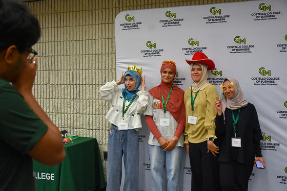 Four students pose in front of the step and repeat