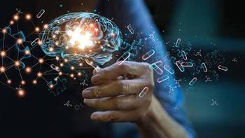 Stock image of a person's hand held out, a computer rendered brain hovering atop it. Outlines of puzzle pieces and chemical structures overlap the image.