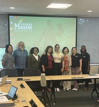 Eight people pose in a classroom