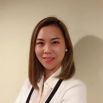 A woman in a white top in front of a beige background smiles at the camera.