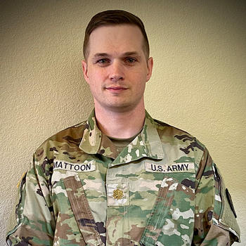 A man in Army fatigues gazes at the camera.