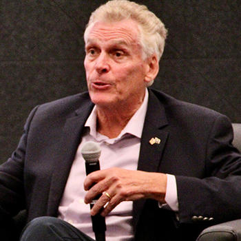 A man holding a microphone gestures with his hand.