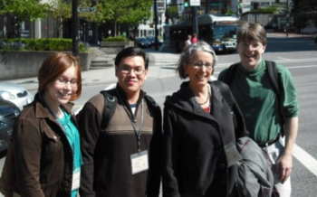 Four people with conference badges pose for a picture near a street intersection.